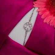 A sterling silver charm bracelet with a butterfly design, displayed on a pink fabric surface.